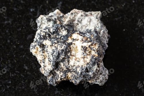 Preview: sample of raw cryptomelane rock on black granite