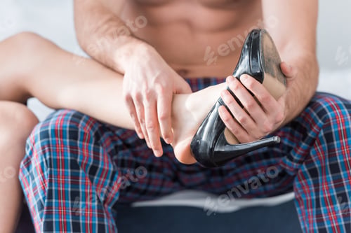 Preview: cropped view of muscular boyfriend wearing shoe on leg of girlfriend