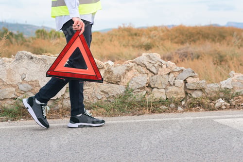 Preview: Unrecognizable man in reflective vest holding warning triangle