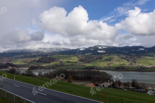Preview: mountainous landscape in Switzerland covered with snow and partly in the clouds with Greyerzersee