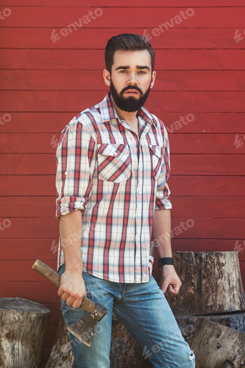 Preview: Handsome bearded man in checkered shirt with axe
