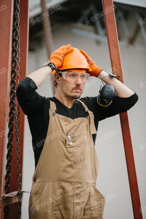 Preview: A construction worker in a protective helmet and glasses at the construction site of a grain silo.