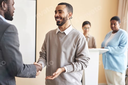 Preview: Happy young man with microphone shaking hand of colleague