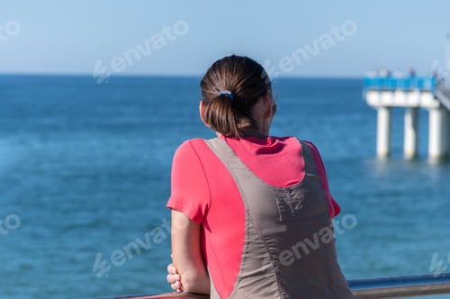 Preview: Woman dreams of traveling and looks at sea. Rear back view, copy space
