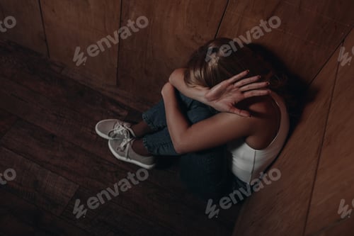 Preview: High angle view of victim with obscure face showing stop and sitting in corner