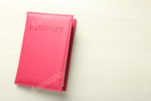 Preview: Passport in bright pink cover on white wooden table, top view. Space for text