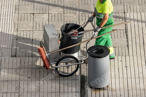 Preview: Sweeper worker pushing a cart on a city sidewalk