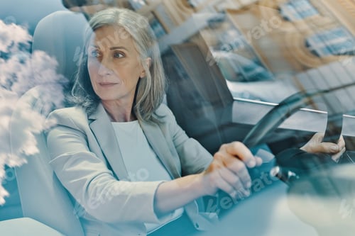 Preview: Mature beautiful woman in smart casual wear looking away while driving car