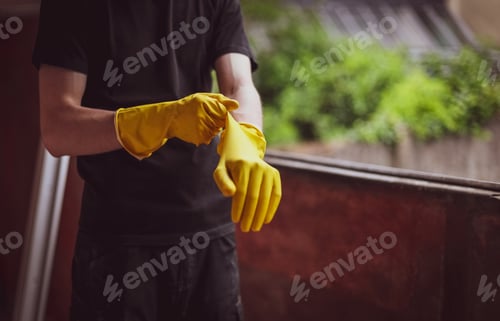 Preview: Caucasian male builder wears yellow gloves.