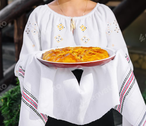 Preview: Traditional homemade sponge cake held by woman in folk costume