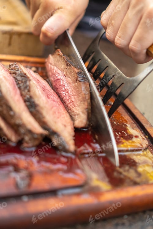 Preview: Man cutting cooked meat during a barbecue in the garden