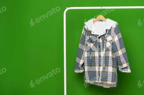 Preview: Kids winter coat hanging on hanger against green wall in studio