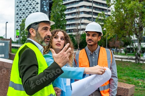 Preview: Architects discussing urban planning with blueprint on construction site