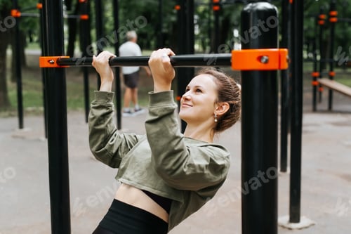 Preview: Training, fitness, sports, outdoor physical exercise. Athletic young woman doing pull-ups on