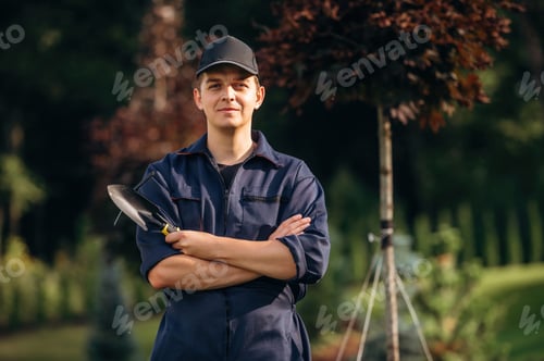 Preview: Standing with arms crossed. Professional gardener is on the lawn