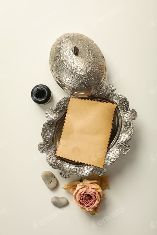 Preview: Silver box with vintage paper and rose on white background, top view