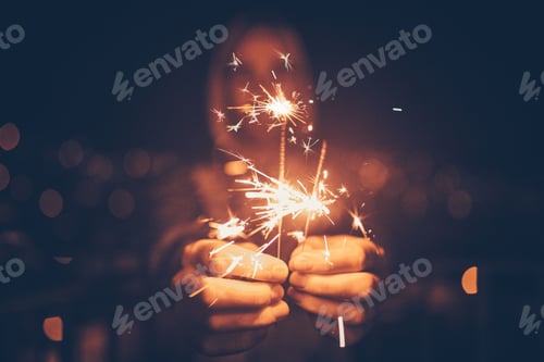 Preview: Man holding sparklers in hand at night