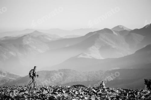 Preview: Male backpaker walking on the rocky top of the mountain