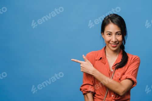 Preview: Asian lady smiling with cheerful expression, shows something amazing at blank space.