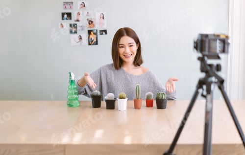 Preview: Asian girl vlogger influencer smiling record video camera filming for live sell and talking cactus