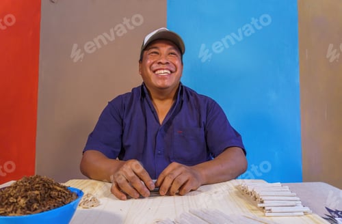 Preview: Hispanic man making hand-wrapped cigarettes on a table