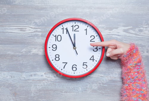 Preview: Female hands holding clock on a table.
