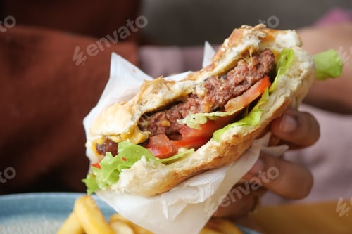 Preview: hand holding beef burger on table close up