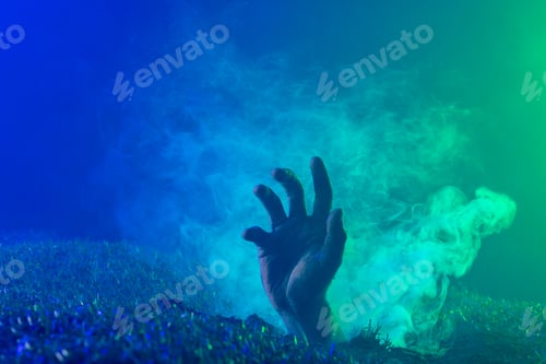 Preview: Composition of hand raising from grass with smoke on black background