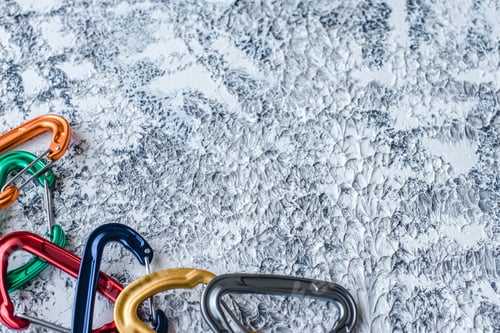 Preview: Isolated photo of climbing equipment. Part of carabiner lying on the white and grey colored surface