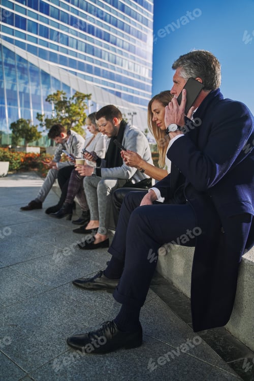 Preview: group of businessmen sitting on their break talking on the phone
