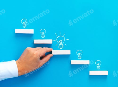 Preview: Businessman hand arranging wood block stacking as step stair with lightbulb.