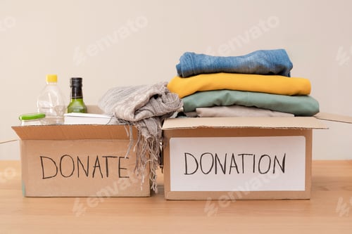 Preview: Two Cardboard boxes overflowing with donated clothes, food, and supplies for charity