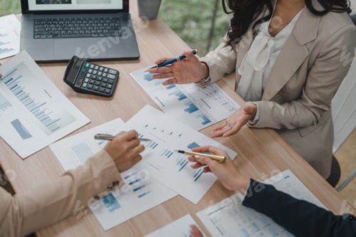 Preview: Businesswomen working together analyzing financial charts and graphs in office meeting