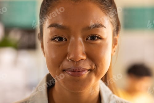Preview: Smiling teenage girl in high school classroom, looking confidently at camera