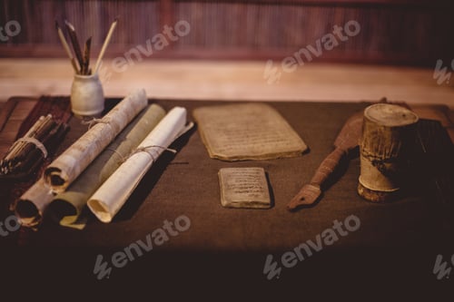 Preview: Closeup of parchment rolls with ancient tools on the table under the lights