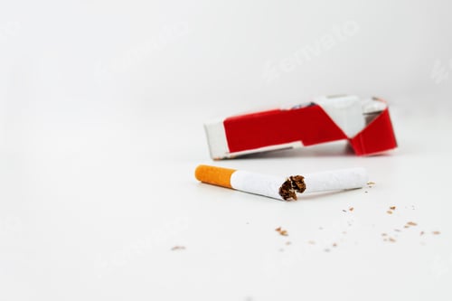 Preview: A pack of cigarettes on a white background and a broken cigarette in the foreground.
