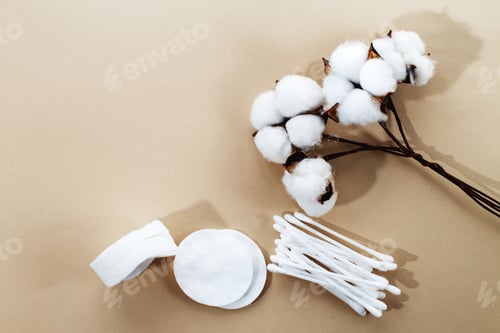 Preview: fluffy cotton flower cotton pads and cotton swabs on beige background with copy space.