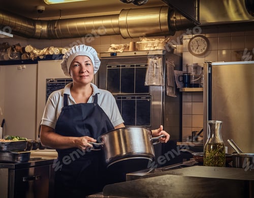Preview: A middle age cook wearing a uniform holding a pan at restaurant's kitchen.