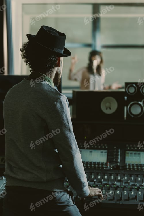 Preview: handsome sound producer in hat recording song at studio