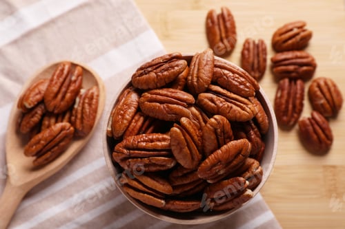 Preview: Tasty pecan nuts with bowl, spoon and cloth on wooden table, flat lay