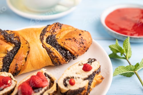Preview: Sweet bun with strawberry jam on a blue wooden background, side view, selective focus.