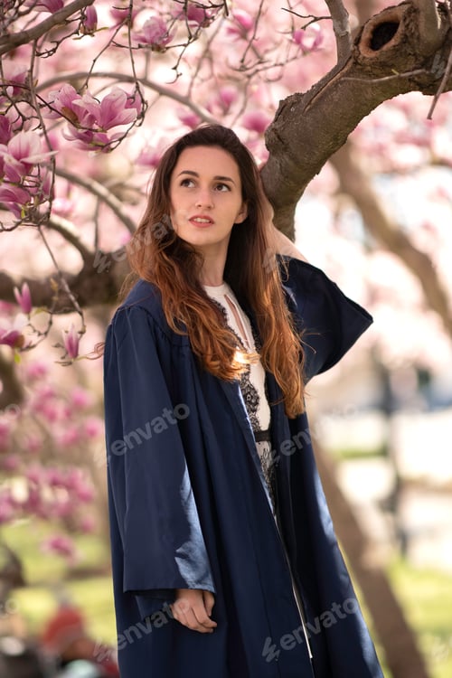 Preview: Female graduate in a blue gown in the cherry blossoms