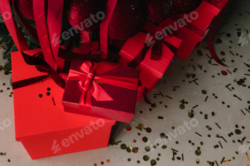 Vista previa: Regalos de Navidad debajo del árbol con cintas, lazos y adornos.