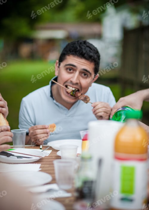 Preview: Man eating in a barbecue brunch outside with friends