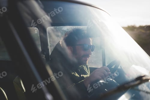 Preview: Man wearing sunglasses driving car in sunlight