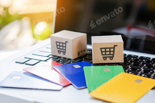 Preview: Shopping online. Credit card and cardboard box with a shopping cart logo on laptop keyboard.