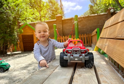 Preview: A little cute boy of one and a half years plays with toy car at the playground.