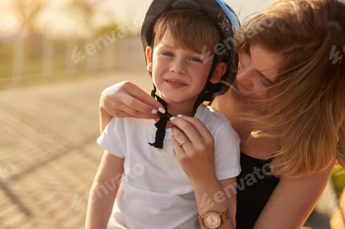 Preview: Woman Helping Child Secure Helmet Outdoors