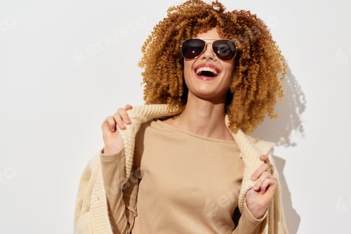 Preview: Fashionable model wearing sunglasses with curly hair, posing against a white background, exuding