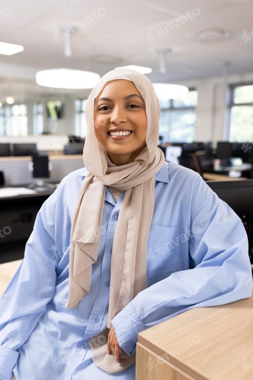 Preview: Vertical image of happy middle-eastern businesswoman in hijab looking at camera in office